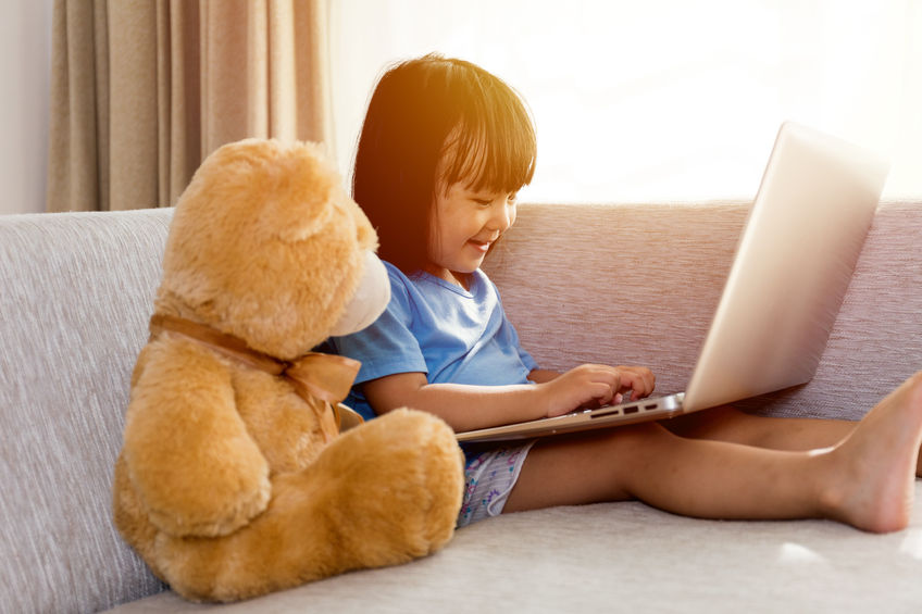 Girl, computer and teddy bear