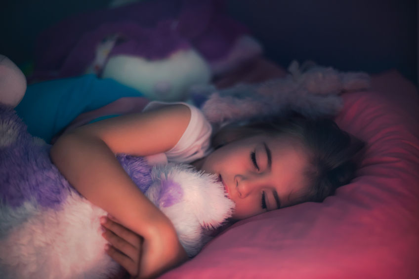 Una niña duerme con su peluche fuera de su casa.