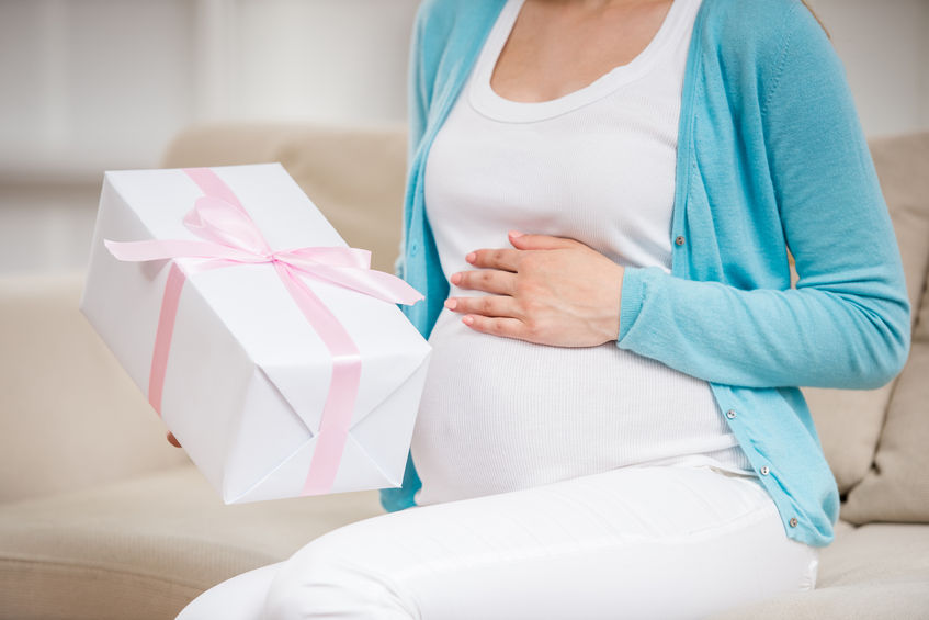Una embarazada recibe un regalo para recién nacido.