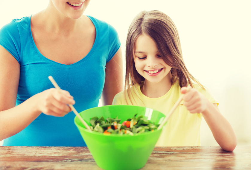 Una niña prepara la ensalada con su madre