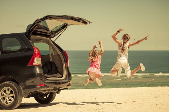 Dos niñas llegan felices a la playa en coche.