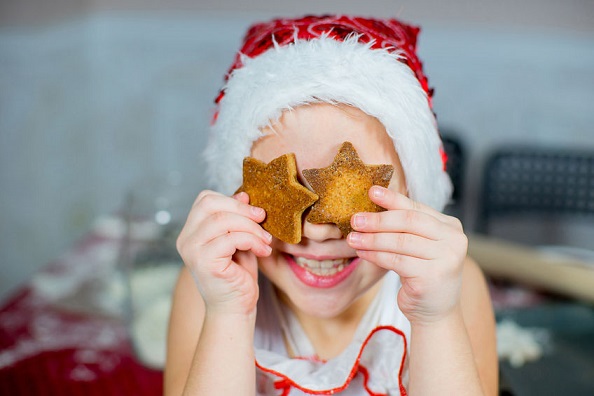 Una niña con dos galletas de navidad hechas por ella.