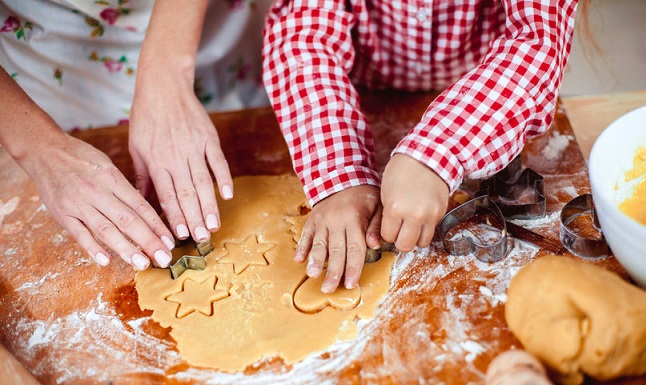Un niño ayuda a su madre a hacer galletas de navidad.