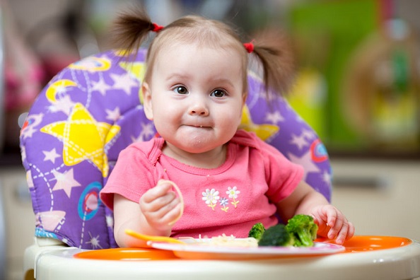 Una niña come sola alimentos sólidos