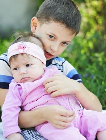 Un niño coge en brazos a su hermana pequeña.