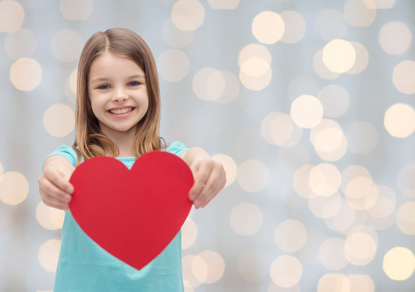 Una niña sujeta un corazón rojo por San Valentín.