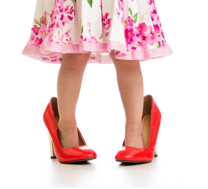 Una niña sobre unos zapatos de tacón.