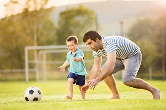 Un padre juega con su hijo al fútbol.
