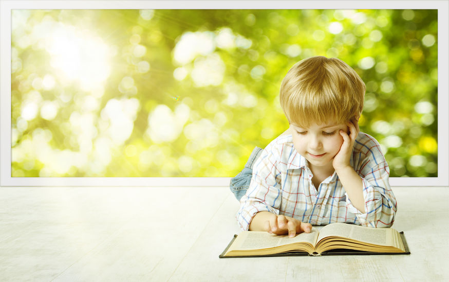 Un niño lee un libro infantil.