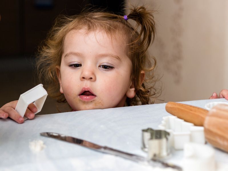 Niña bebé con riesgo de accidente con objetos cortantes en la cocina