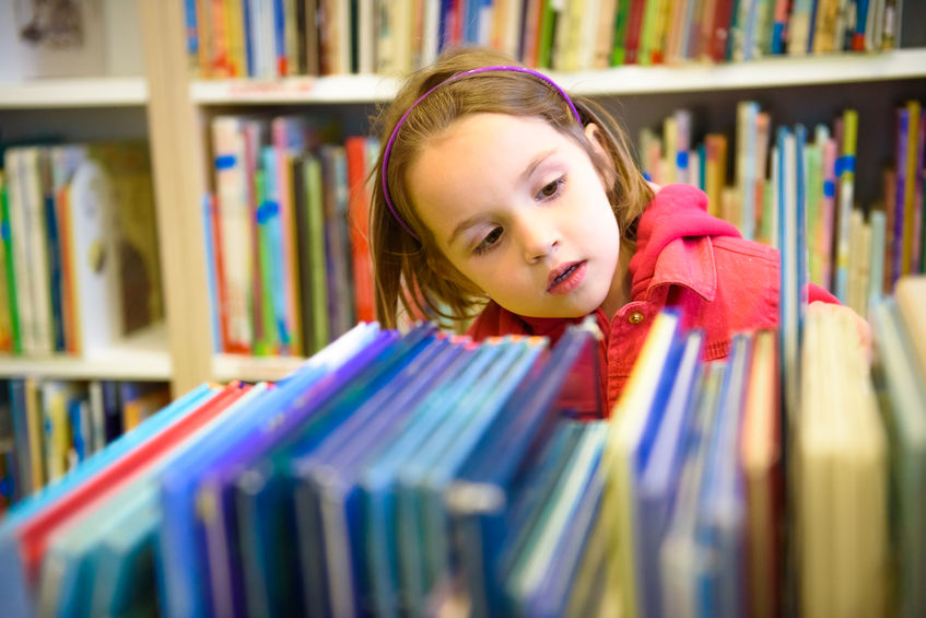 Niña buscando libros en la biblioteca