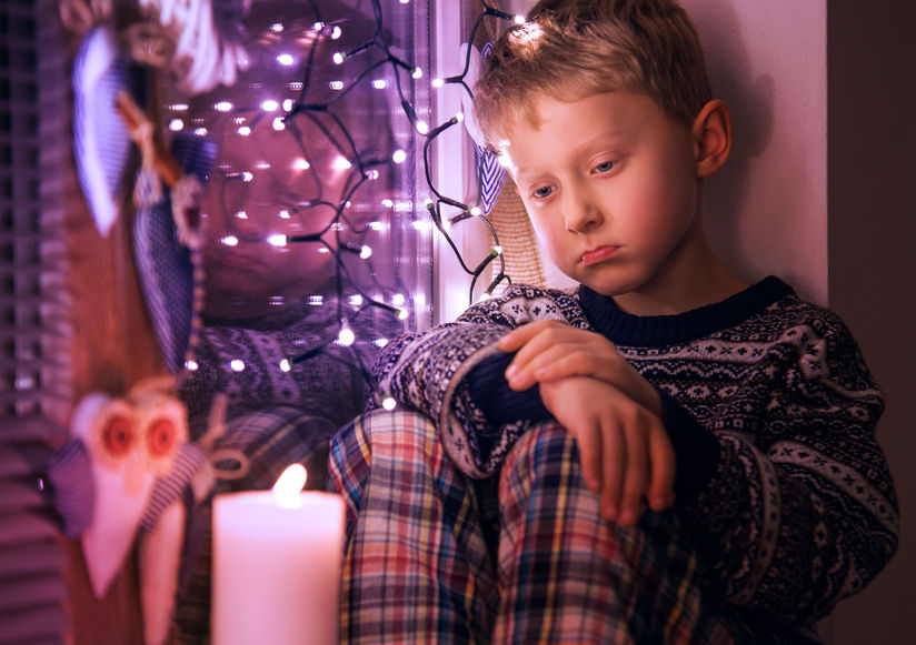 Un niño triste espera los regalos en Navidad