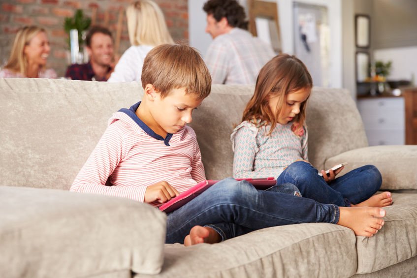 Niños que usan smartphones y tablets en el salón de casa