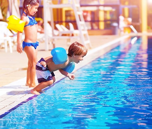 Dos niños juegan en el borde de una piscina.