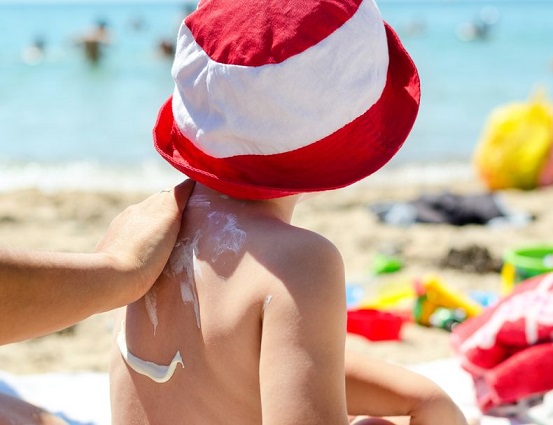 Una madre aplica el protector solar a un niño.