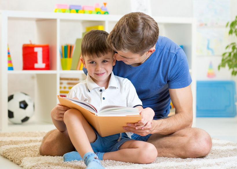 Un padre lee un libro con su hijo.