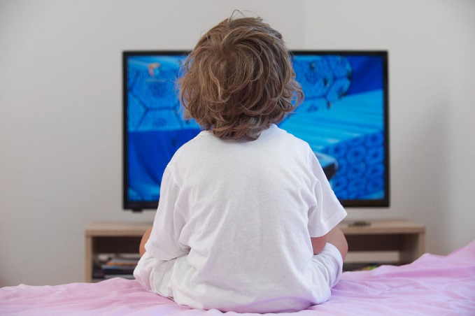 Un niño ve la tele durante la cama en verano.