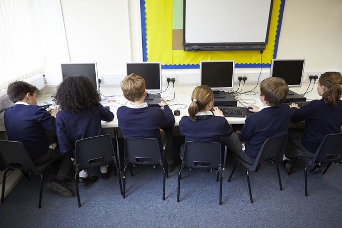 Varios niños que usan uniforme en el cole en una clase de informática.