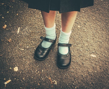 Una niña muestra los zapatos de su uniforme.